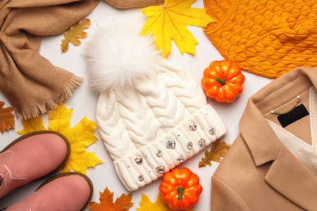 A set of warm autumn-winter clothes with fallen leaves and pumpkins on a white background. Flat lay top viewの写真素材