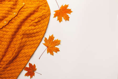 Autumn concept. Yellow-orange sweater with maple leaves on a light gray background. Flat lay top view copy spaceの写真素材