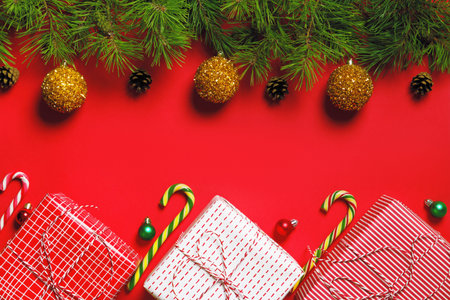 Christmas composition banner. Christmas boxes with gifts and fir branches on a red background. Flat...