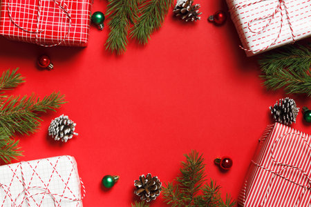 Christmas composition. New Years boxes with gift fir branches on a red background. Frame border flat...