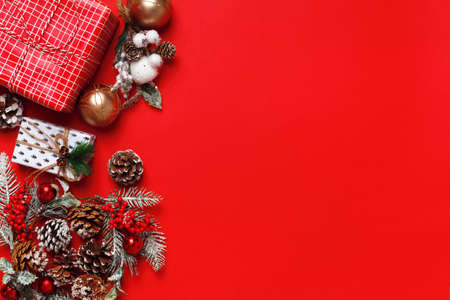 New Year's composition. Christmas boxes with gift fir branches with cones on a red background. Frame border flat lay top view copy spaceの写真素材