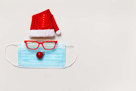 Christmas hat of santa claus with glasses protective mask on light gray background. Copy spaceの写真素材