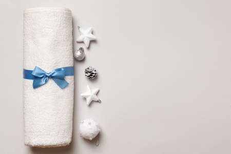 Fresh white terry towel with a bow rolled up on a light gray background. Christmas tree decorations pine cones. Copy spaceの写真素材