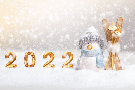 Winter new year christmas composition. Lettering 2022 in gold and a toy penguin with skis on the...
