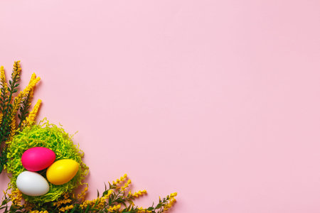 Top view of easter eggs and flower twigs on pink background. Flat lay with copy space
