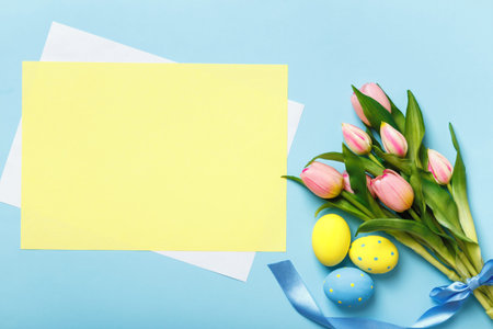 Easter composition. Eggs flowers tulips on a blue background. Empty sheet of paper with space for...