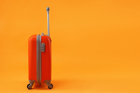 Orange suitcase of travel bags on a yellow background with copy space. The concept of summer time, vacation, tourism.の写真素材