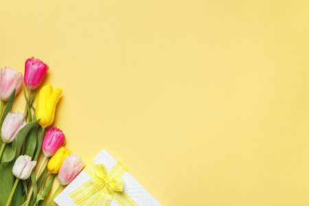 greeting card. Gift bouquet of tulips on yellow background with copy space.
