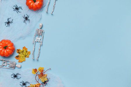 Halloween composition. On the web are skeletons of pumpkin spiders. Decor on a blue background with...