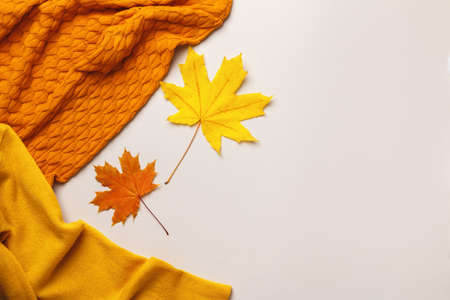 Yellow and orange sweater with fallen autumn maple leaves on a gray table.の写真素材