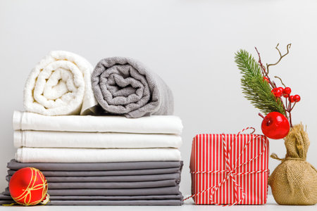 Stack of bed linen, bed sheet and folded rolls of towels on a table with Christmas decorの写真素材