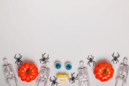 Halloween pumpkin spider skeletons. Top view of border decor on gray background.