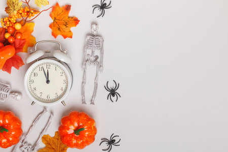 Alarm clock with fallen leaves pumpkins skeletons spiders. Transitional change of autumn time, change of seasons halloweenの写真素材