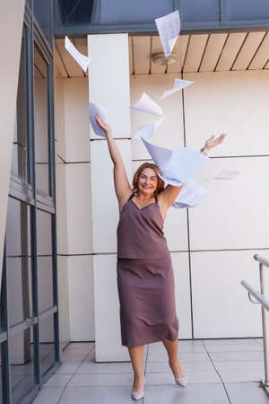 a busy young woman with papers in her hands, a happy business woman tosses the papers upの写真素材