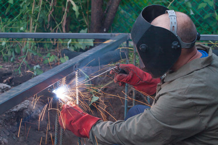 electric arc welding of metal structures by workers in protective suits