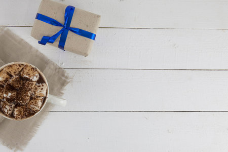 drink with marshmallows on wooden surface and giftの写真素材