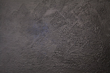 Dark textured concrete background with spot of light and blue tint