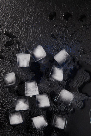 Light ice cubes on dark textured background