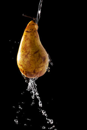 Pear with falling drops of water on a dark backgroundの写真素材