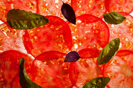 Thin slices of red ripe tomato on a light background with a light