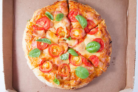 Pizza with tomatoes, sausages and cheese in a cardboard boxの写真素材