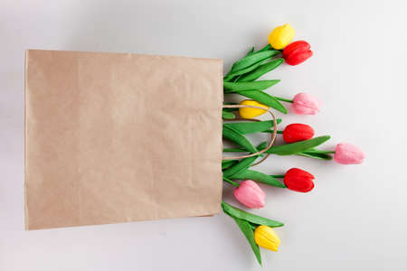 Colorful flowers in a brown craft paper bag with handlesの写真素材