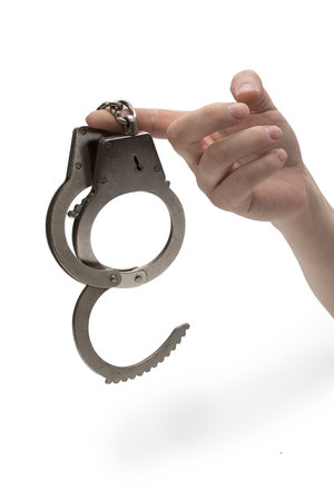 Metal handcuffs with a chain on a light background in a female handの写真素材
