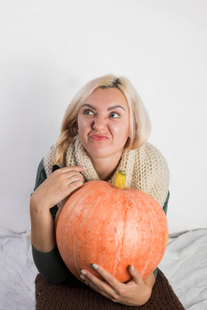 Portrait of beautiful young blonde woman with pumpkin ready for halloween celebration, mockup for postcard and invitation or advertisementの写真素材