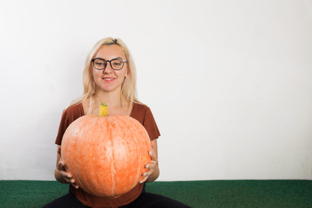 Portrait of beautiful young blonde woman with pumpkin ready for halloween celebration, mockup for postcard and invitation or advertisementの写真素材
