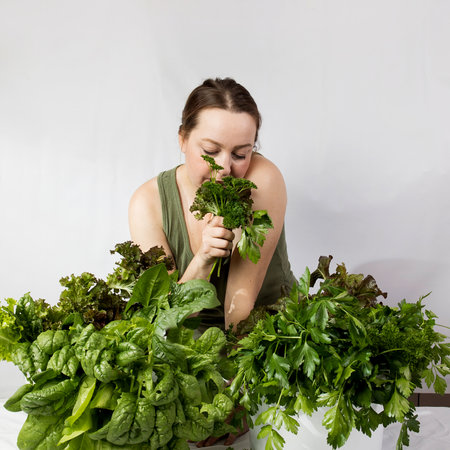 Young woman with a set of green herbs, spinach, lettuce, parsley and ingredients for a healthy diet. High quality photoの写真素材
