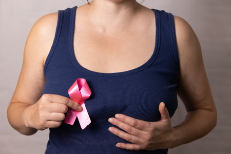 A woman shows a pink ribbon, symbolizing her commitment to breast cancer awareness and support initiativesの写真素材