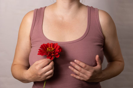A serene image shows a woman holding a vibrant red flower, symbolizing beauty and the bond between nature and emotionの写真素材