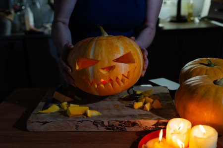 A person is meticulously carving a pumpkin for halloween that has a detailed face expertly carved into its surface, creating a spooktacular designの写真素材