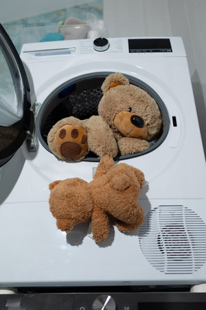 A group of playful teddy bears are all set and ready for a wash inside of a sleek and modern washing machineの写真素材