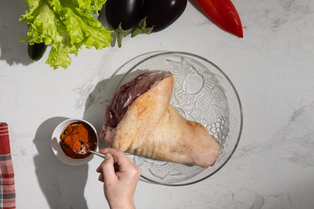 A person is carefully dipping a delicious piece of meat (pork knuckle) into a bowl filled with flavorful sauce, enhancing its taste and presentationの写真素材