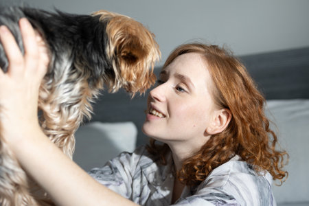 A woman is sharing a truly joyful and heartwarming moment with her beloved small dog in a cozy home settingの写真素材