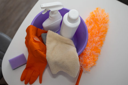 A colorful collection of cleaning supplies neatly organized in a purple bucket for effective home...