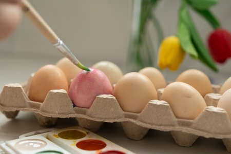 A joyful scene depicts painting pastelcolored Easter eggs, with vibrant tulips blooming in the backgroundの写真素材