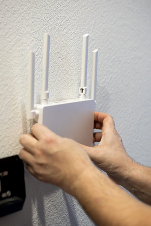An individual installs a modern WiFi router on the wall, optimizing network connectivity for better...