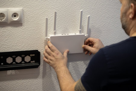 A man is carefully mounting a wireless router onto a wall in a sleek and modern interior space of...