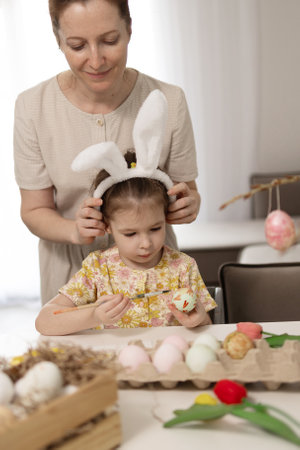 A delightful and joyful moment shared between a mother and her daughter as they decorate colorful Easter eggs at homeの写真素材