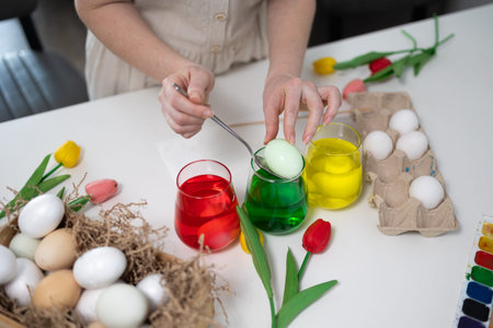 Festive egg dyeing scene with vibrant colors and floral decorations, perfect for Easter...