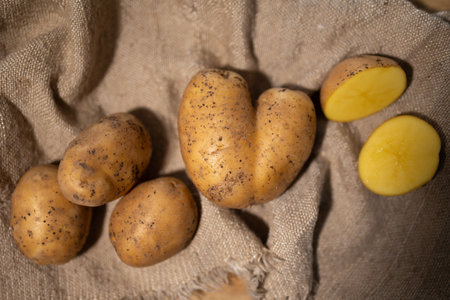 A rustic composition featuring whole and halved potatoes beautifully arranged on a textured burlap surfaceの写真素材