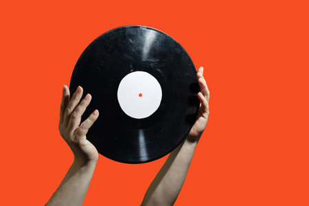 An artistic and captivating shot of hands gently lifting a vinyl record, showcasing a unique modern retro vibeの写真素材