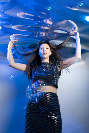 A girl dressed as a mermaid floats effortlessly in water, showcasing her fabulous outfit while...