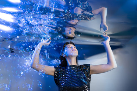 A girl dressed like a mermaid captures attention while submerged in clear water. Bubbles surround...