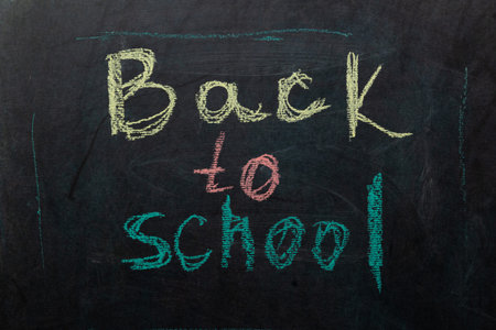 Bold, colorful chalk writing on a blackboard announces the return to school. Students eagerly anticipate learning and reconnecting with friends in the new academic year.の写真素材