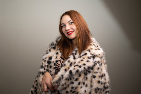 A confident woman with a bright smile poses in a leopard print shawl, showcasing her bold fashion and personalityの写真素材