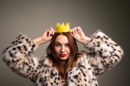 A stylish and fashionable woman with a funny delusion of grandeur who is adorned with a crown and wearing a leopard print coat, radiating confidenceの写真素材