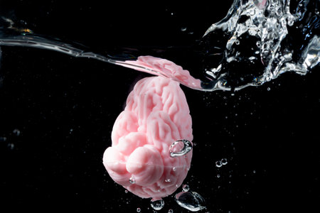 A vibrant pink brain is submerged in clear water, producing splashes and bubbles that emphasize mental energy and vigor, creating a captivating visual interplay of mind and motion.の写真素材